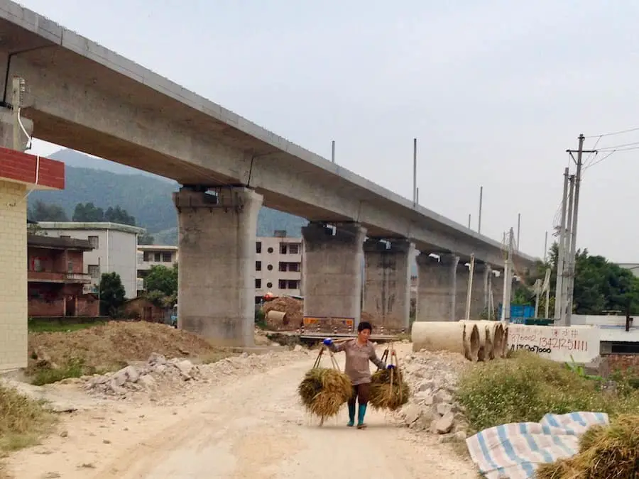 A woman carrying things with a new high-speed train track in background