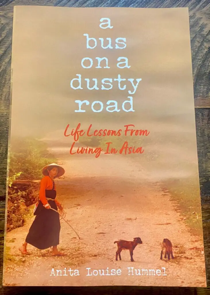A BUS ON A DUSTY ROAD BY ANITA LOUISE HUMMEL, FRONT COVER OF GIRL ON ROAD WALKING WITH ANIMALS AND DUST