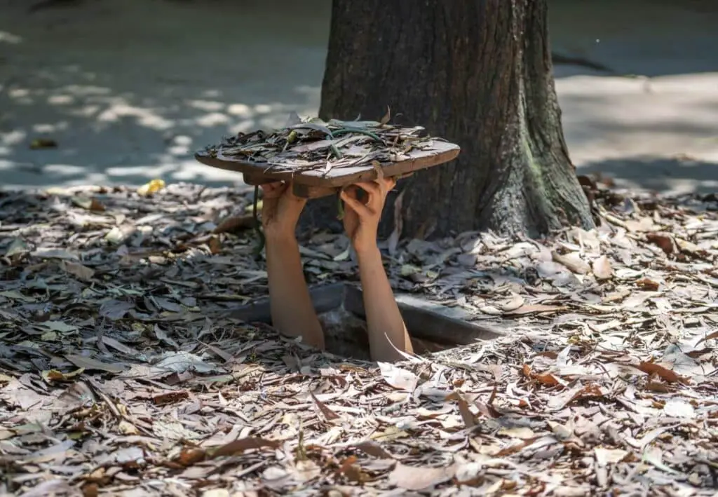 a person's hands holding a square object in a hole in the ground