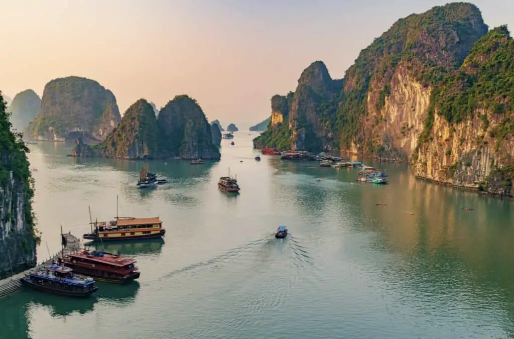 boats in a body of water with mountains in the background with Ha Long Bay in the background